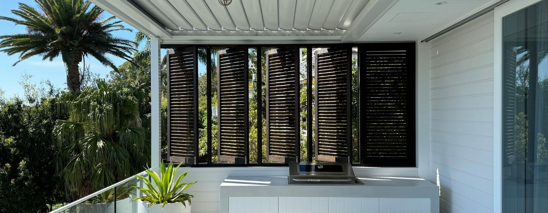 Covered Patio With White Counter, Potted Plant, and Black Louvered Shutters — Fineworx Joinery in Warnervale, NSW