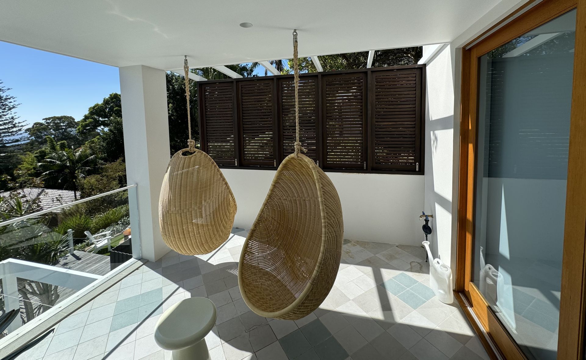 Two Woven Hanging Chairs on a Sunny Balcony With White Walls, Glass Railing — Fineworx Joinery in Warnervale, NSW