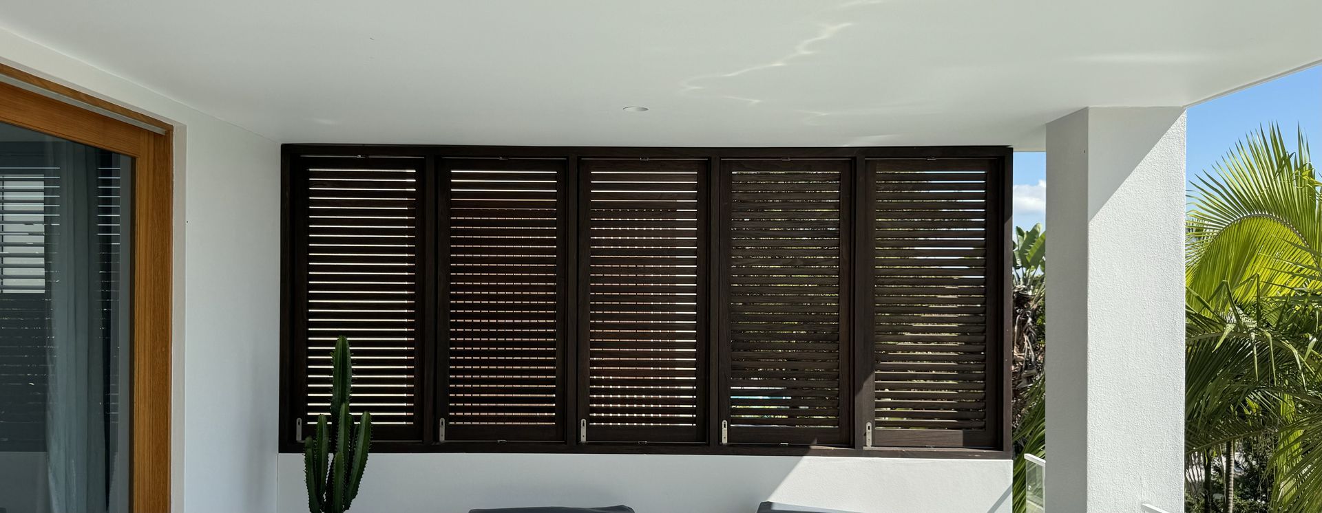 Modern Porch With Dark Wooden Louvered Shutters and a Potted Plant — Fineworx Joinery in Warnervale, NSW