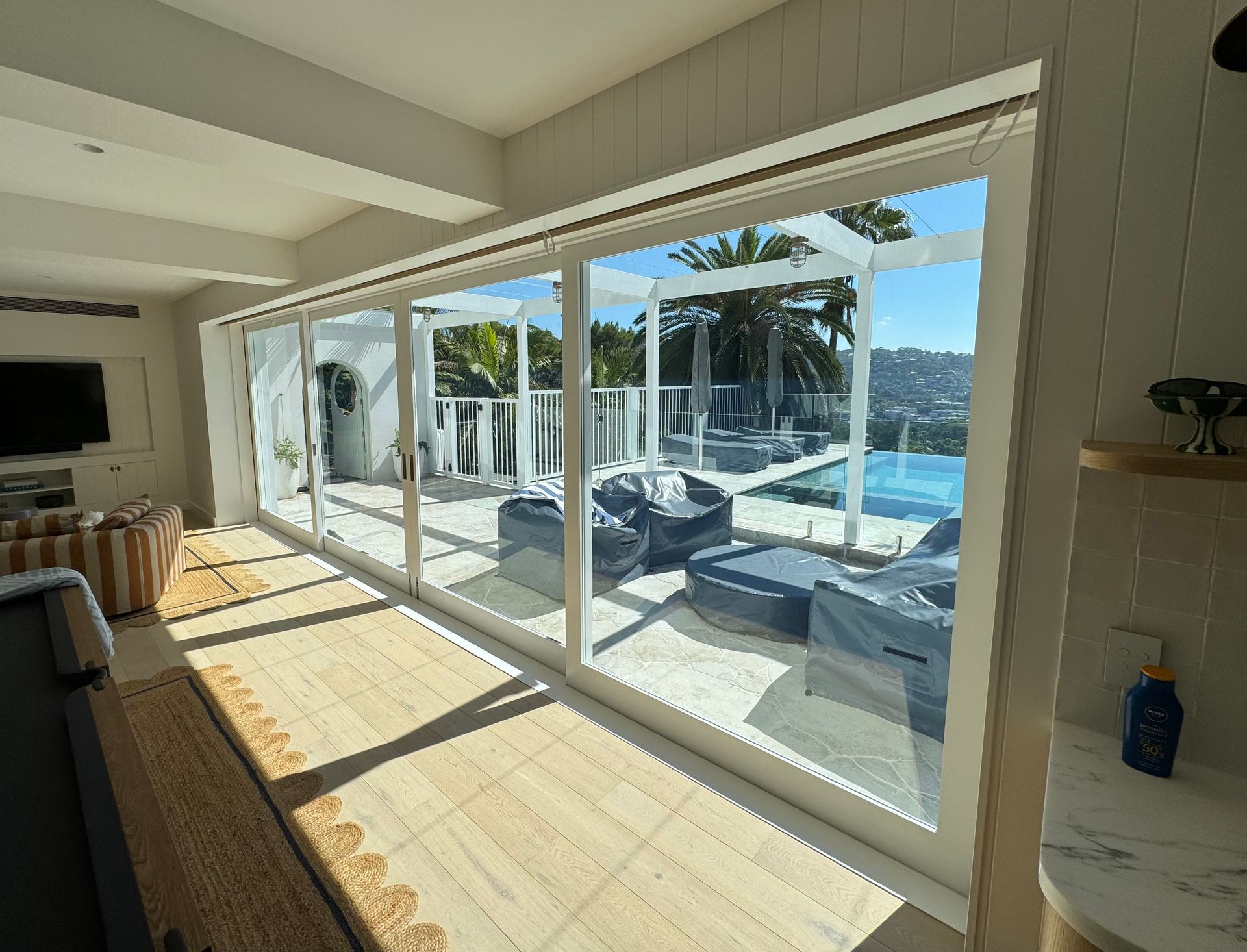 Bright Living Room Opening to a Sunny Poolside Patio With Ocean Views and Lounge Chairs — Fineworx Joinery in Warnervale, NSW