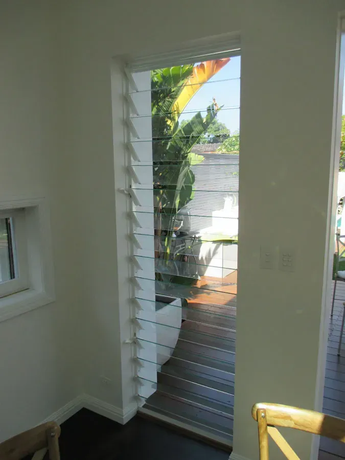 Interior stair landing with a door opening to a bright outdoor patio and tropical plants — Fineworx Joinery in Warnervale, NSW