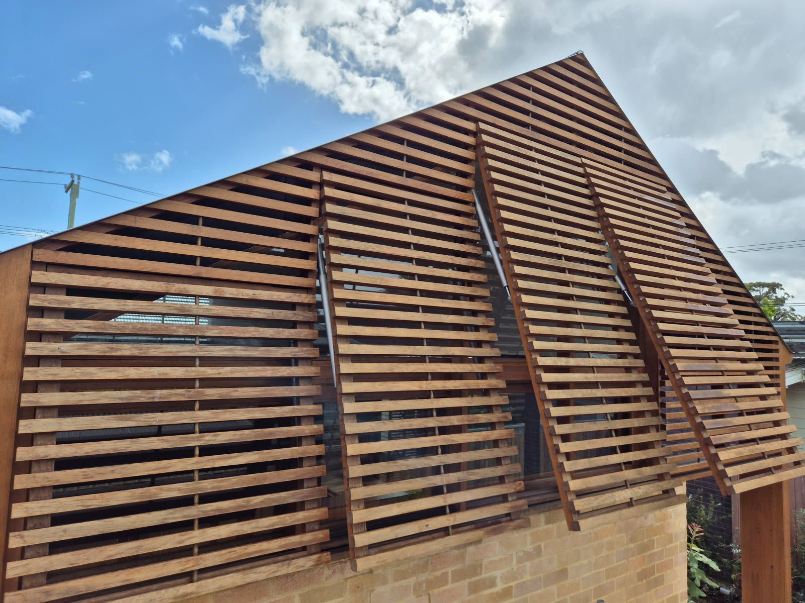 Wooden Slatted House Facade With a Steep Triangular Roof Against a Blue Sky — Fineworx Joinery in Warnervale, NSW