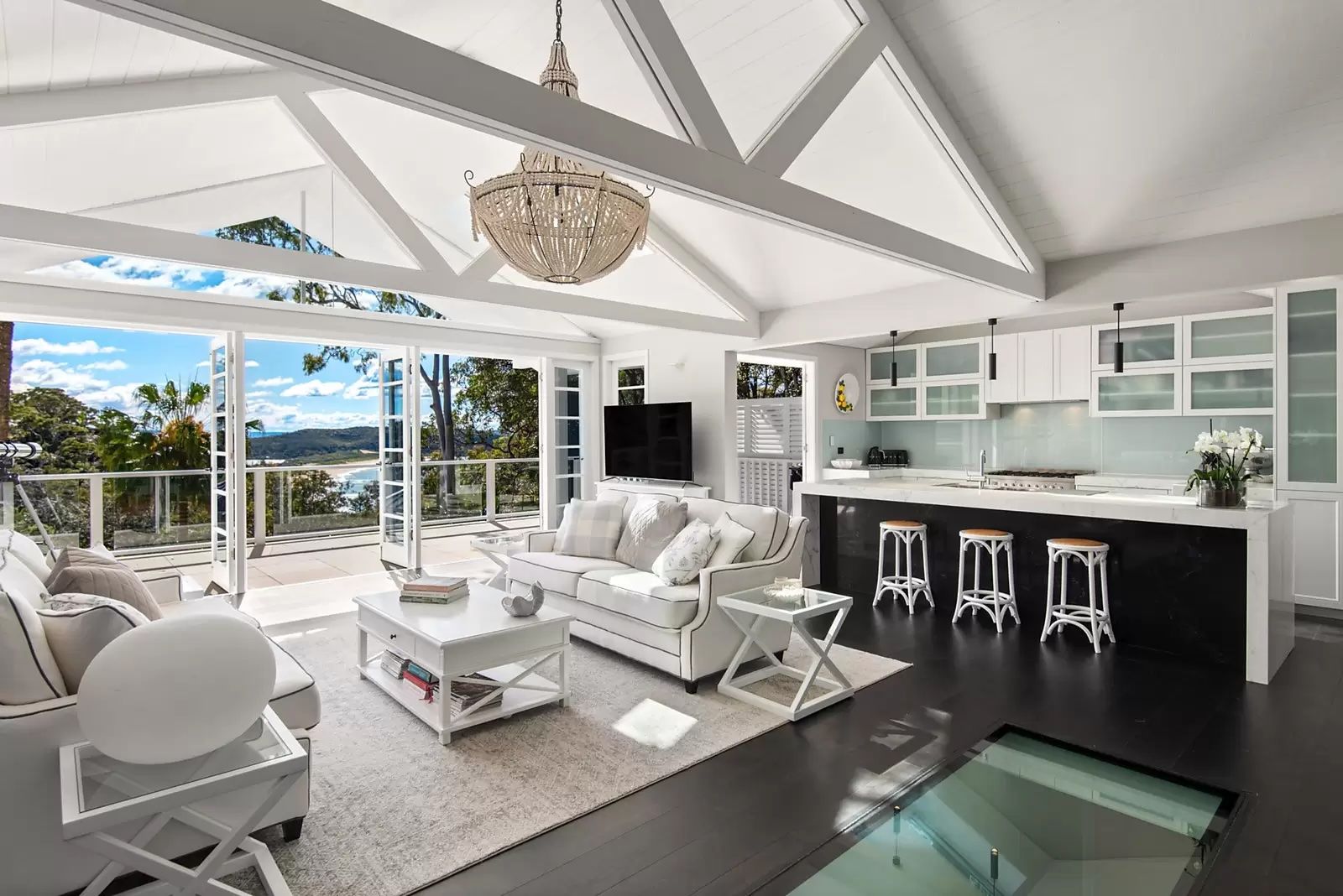 Bright modern living room with white furniture, black fireplace, and large windows opening to an outdoor patio. — Fineworx Joinery in Warnervale, NSW