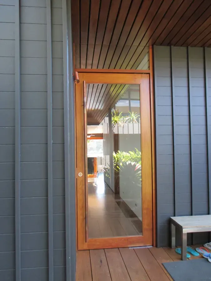 Wood-framed glass door on a modern porch, reflecting an outdoor walkway and greenery — Fineworx Joinery in Port Stephens, NSW