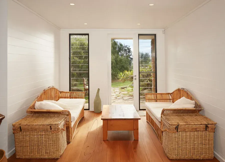 Bright living room with wicker sofas, wooden coffee table, and open doors to a sunny garden. — Fineworx Joinery in Warnervale, NSW