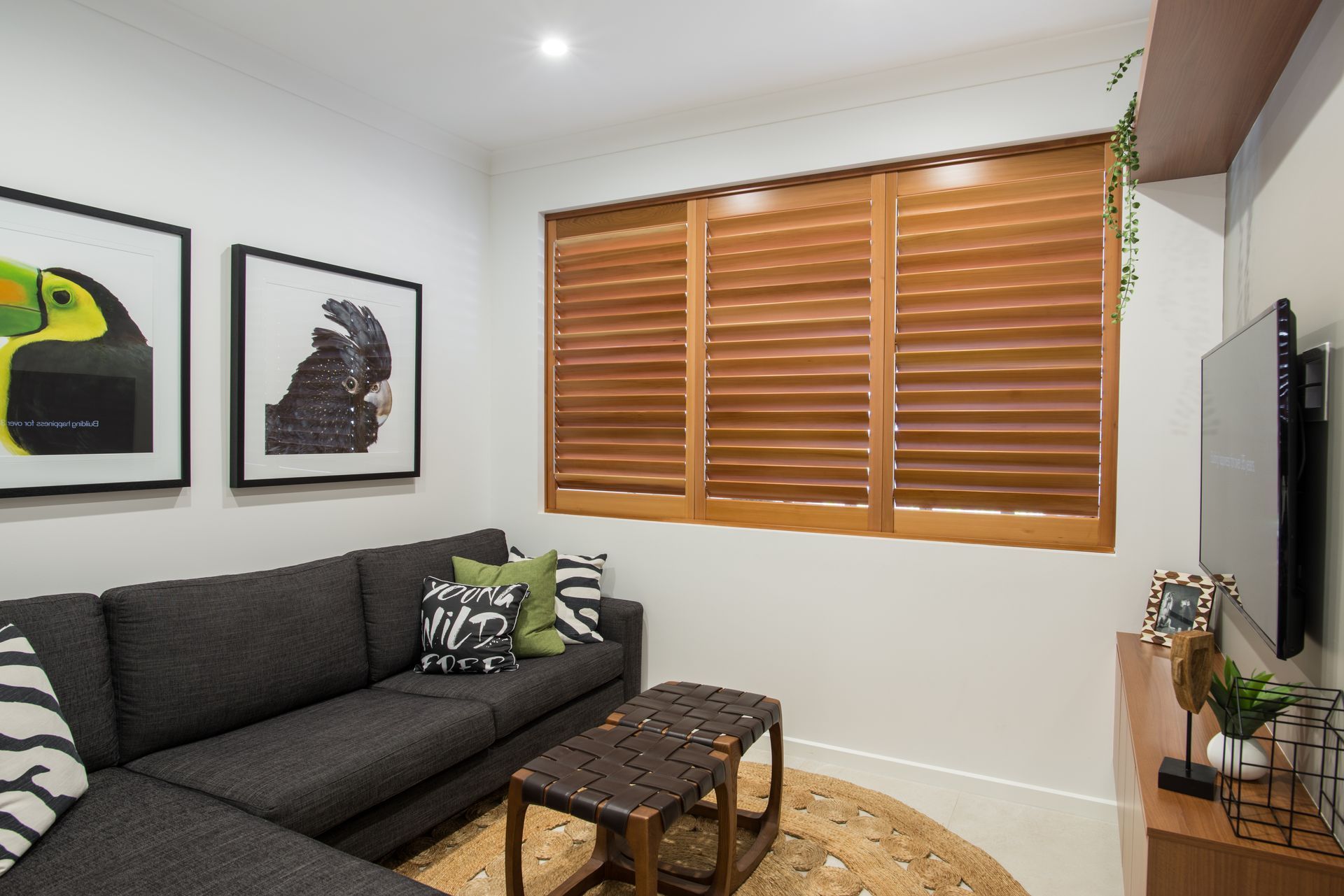Modern living room with gray sofa, framed art, wooden blinds, and a TV console — Fineworx Joinery in Warnervale, NSW