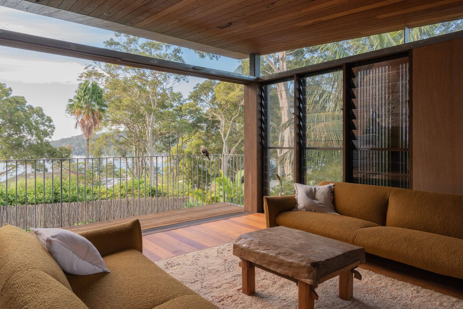 Covered Patio With Brown Sofas, Woven Table, and Open View of Trees and Greenery — Fineworx Joinery in Warnervale, NSW