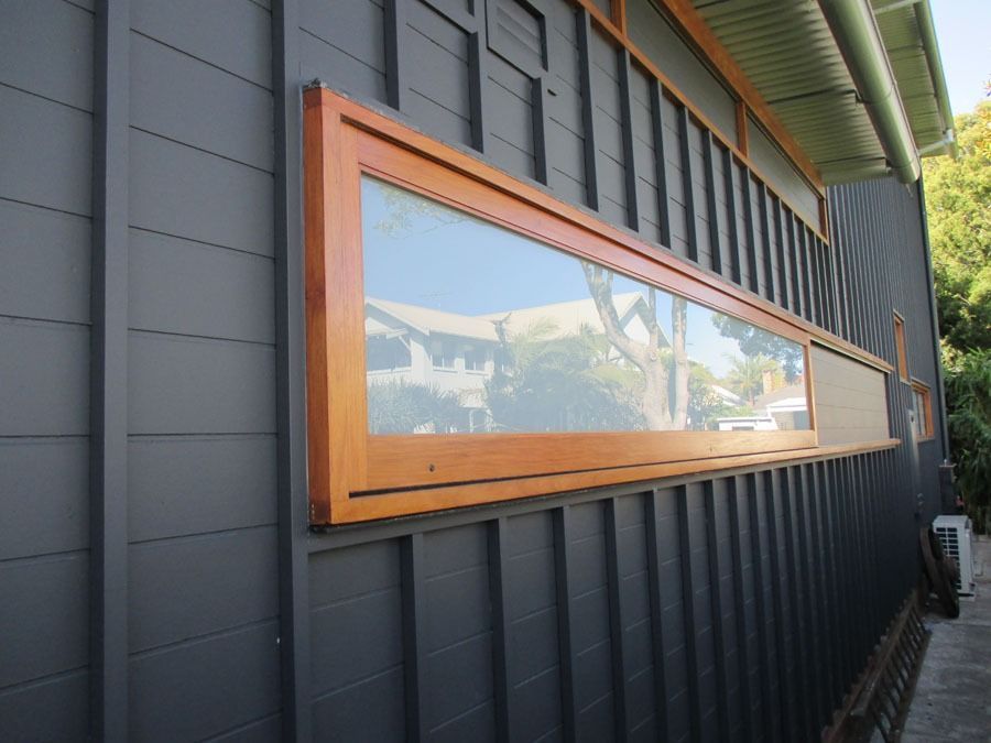 Modern Building Exterior with A Long Wooden Framed Window on Dark Siding — Fineworx Joinery in Warnervale, NSW