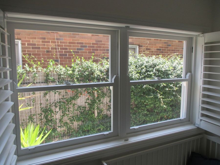 Sunlit Window with White Blinds Overlooking a Brick Wall and Green Ivy Outside — Fineworx Joinery in Warnervale, NSW