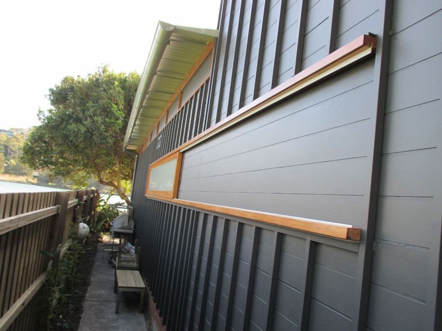 Side View of A Dark House Exterior with A Long Narrow Window and Wooden Trim — Fineworx Joinery in Warnervale, NSW
