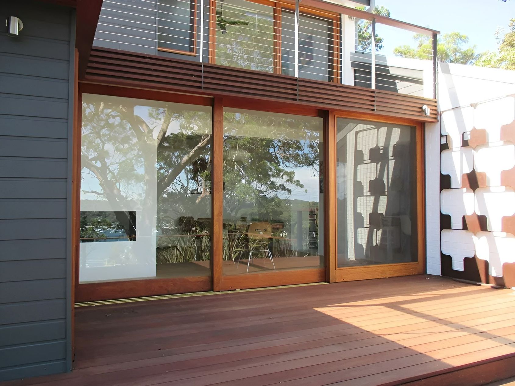 Modern Wooden Deck Beside a Glass Sliding Door and Upper Balcony — Fineworx Joinery in Warnervale, NSW