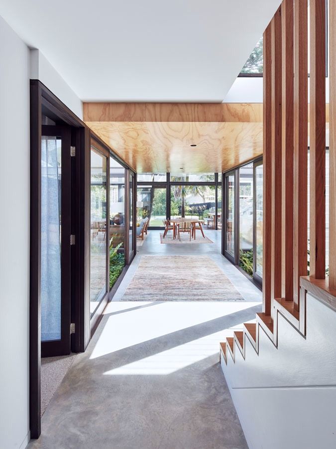 Modern Hallway with Glass Walls and White Stairs Leading to A Sunlit Patio — Fineworx Joinery in Warnervale, NSW