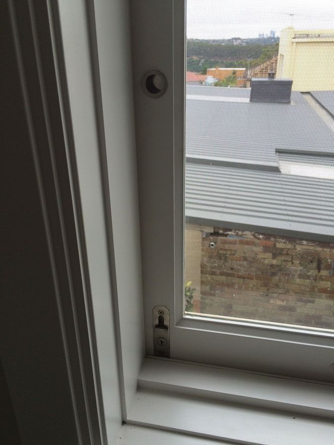 Window with A Mesh Screen Looking out Onto Rooftops and A Stone Wall — Fineworx Joinery in Warnervale, NSW