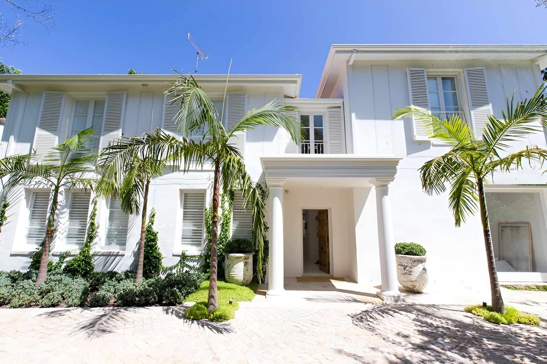 White Modern Villa with Palm Trees and A Central Entrance Under a Clear Blue Sky — Fineworx Joinery in Hunter Valley, NSW