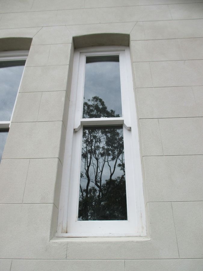 Narrow White Framed Window in A Light Stone Building, Reflecting Trees and Sky — Fineworx Joinery in Warnervale, NSW