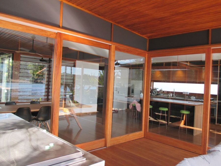 Wood Framed Glass Patio Enclosure with A Wooden Floor and Outdoor Seating — Fineworx Joinery in Warnervale, NSW