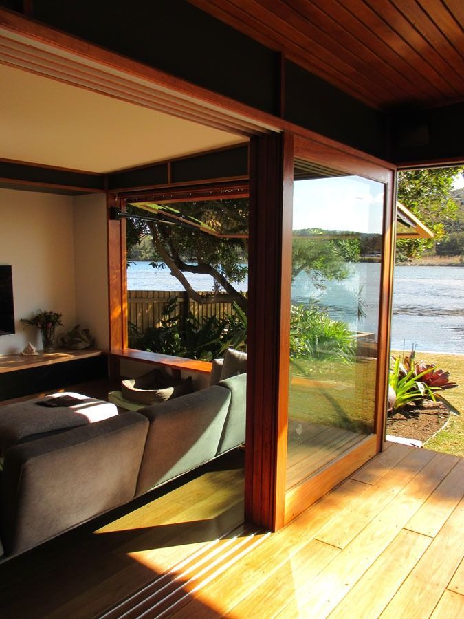Open Wooden Doors to A Sunlit Room Overlooking a Tropical Garden and Water View — Fineworx Joinery in Warnervale, NSW