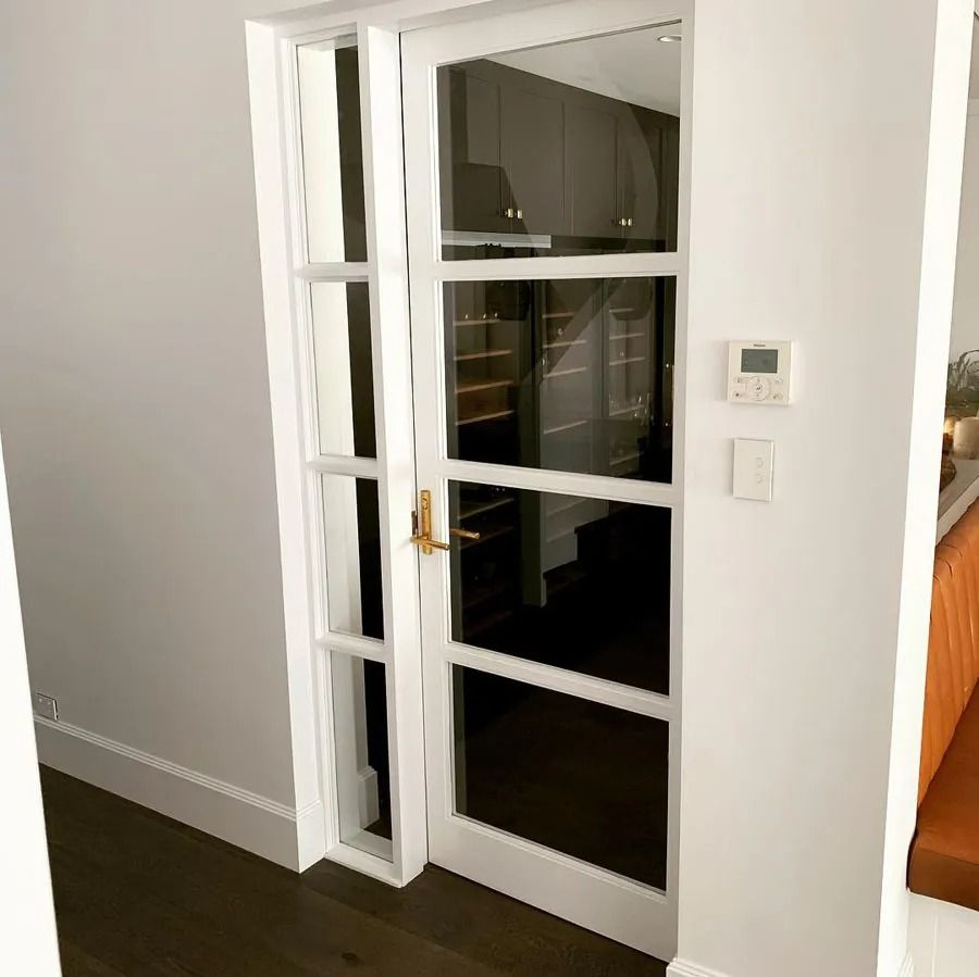 White French Doors Opening to A Dark Kitchen with A Wall Thermostat Beside Them — Fineworx Joinery in Warnervale, NSW