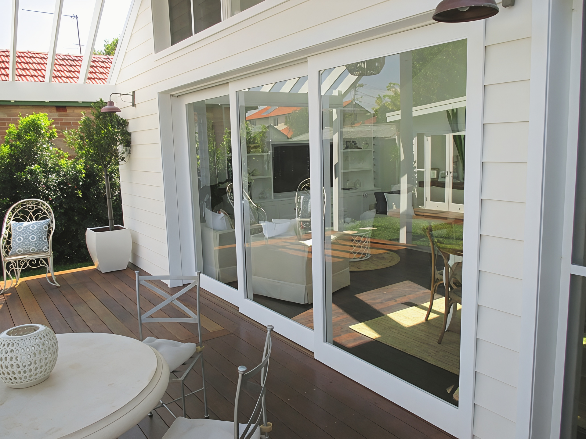 Patio with White Sliding Glass Doors and Outdoor Seating in Bright Sunlight — Fineworx Joinery in Newcastle, NSW
