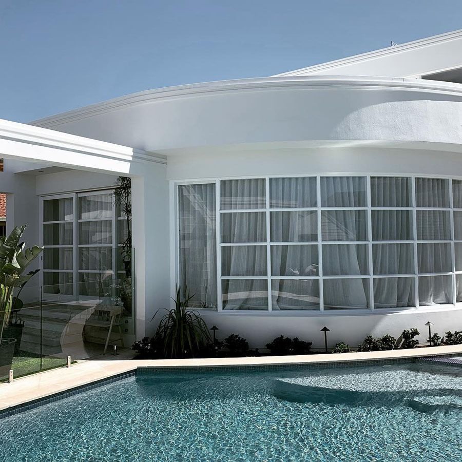 Modern White House with Curved Windows Beside a Turquoise Swimming Pool — Fineworx Joinery in Warnervale, NSW