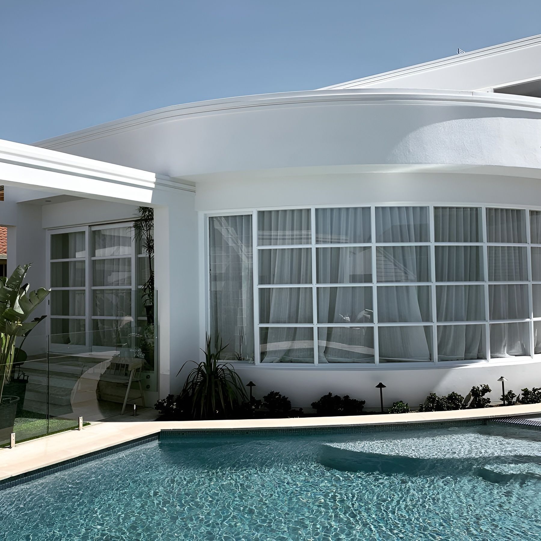 Modern White House with Curved Windows Beside a Turquoise Pool — Fineworx Joinery in Warnervale, NSW