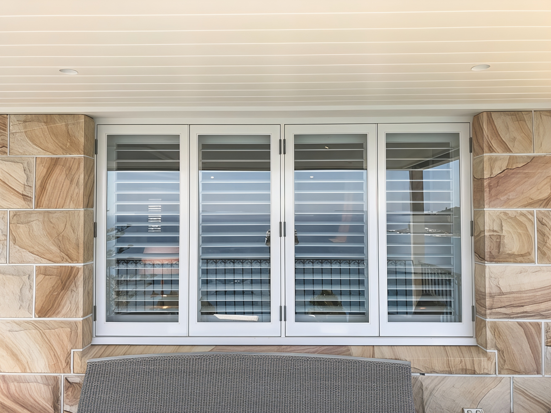 White window shutters set in a stone exterior wall above a textured bench. — Fineworx Joinery in Warnervale, NSW