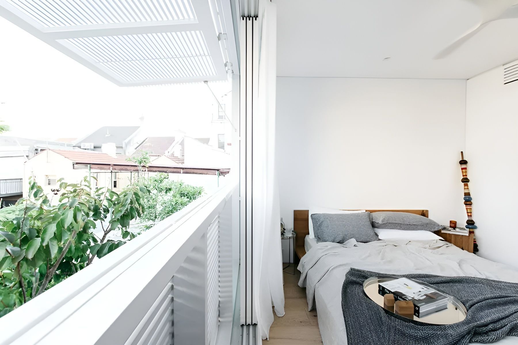 Bright Bedroom with A Bed and A Balcony Overlooking Greenery and Houses — Fineworx Joinery in Warnervale, NSW