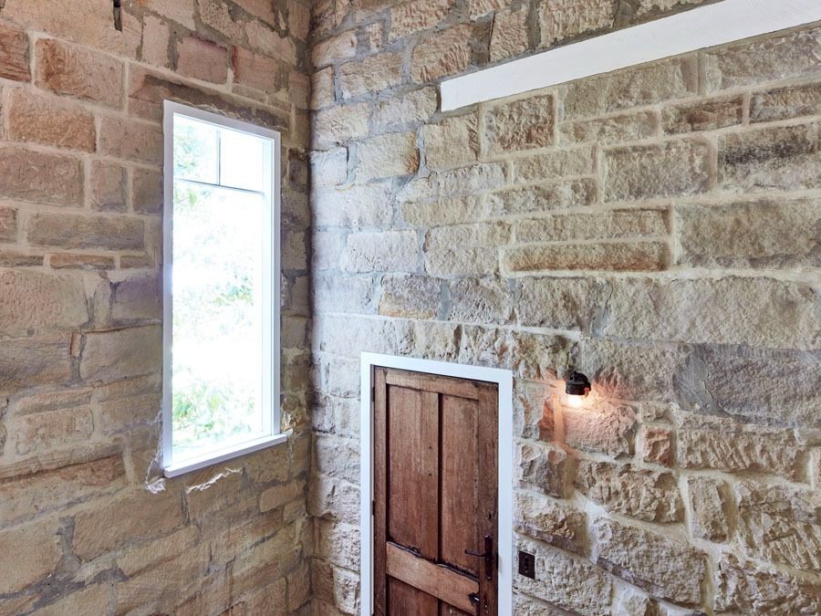 Stone Interior Wall with A Narrow Window and Wooden Door Beneath a Wall Sconce — Fineworx Joinery in Warnervale, NSW