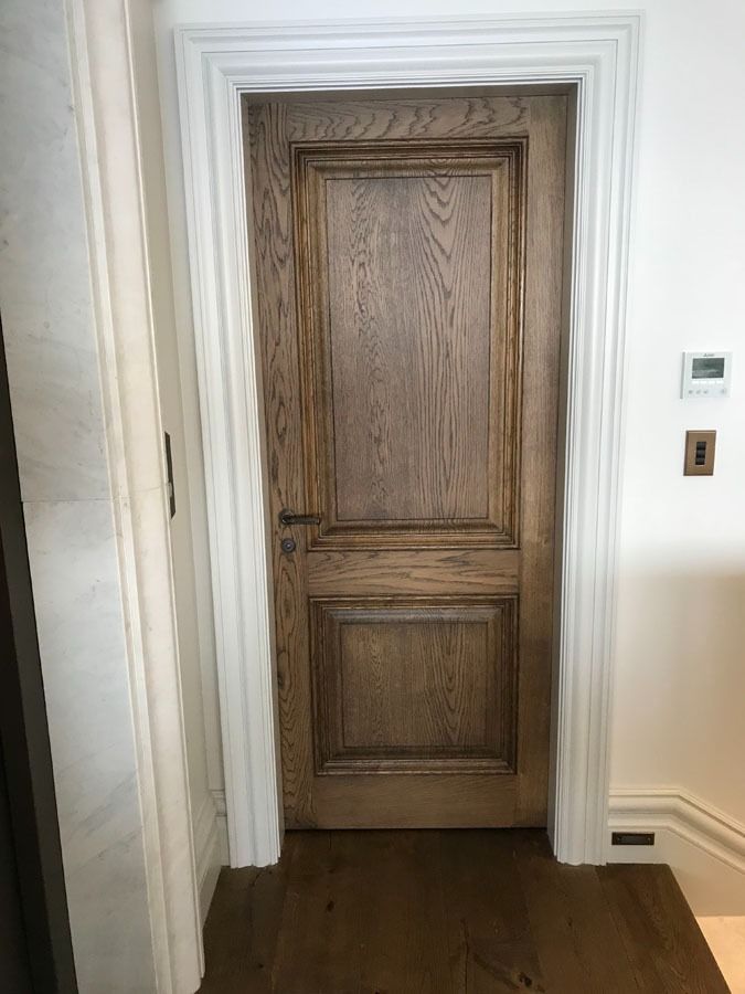 Wooden Paneled Door Framed by White Trim in A Hallway with Dark Wood Flooring — Fineworx Joinery in Warnervale, NSW