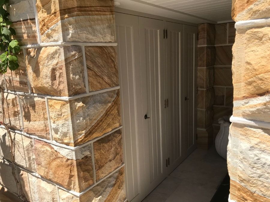 Narrow Outdoor Hallway with Stone Pillars and White Storage Cabinets Under a Covered Roof — Fineworx Joinery in Warnervale, NSW