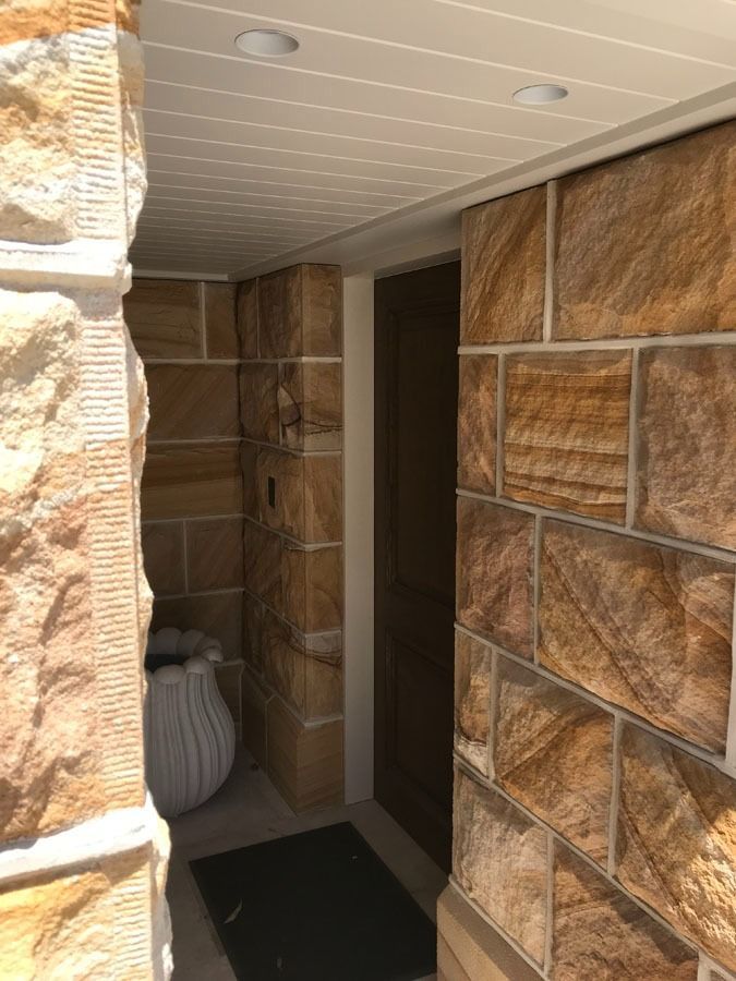 Stone Front Entryway with A Black Mat and A Decorative Planter by A Doorway — Fineworx Joinery in Warnervale, NSW