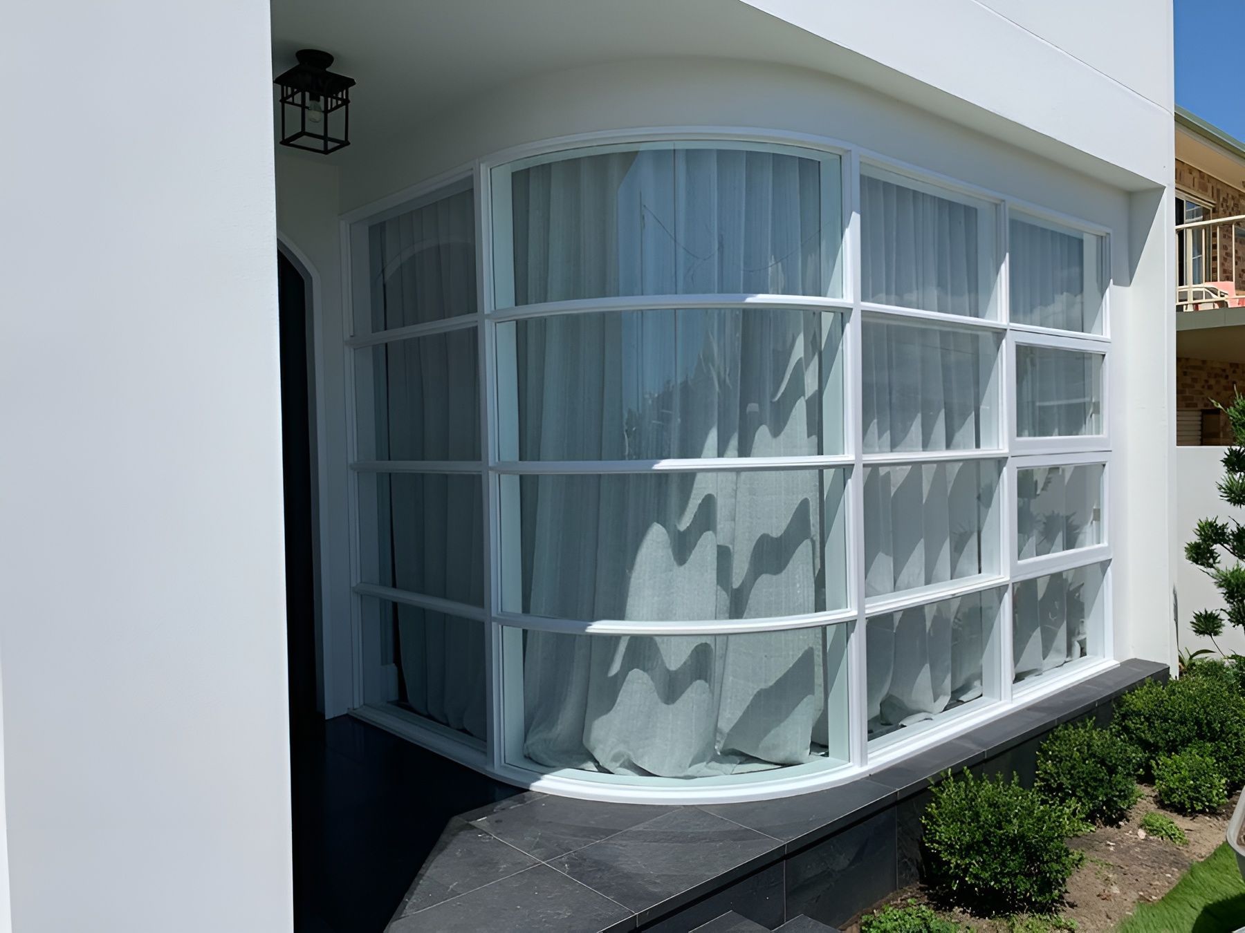 Curved White Building Facade with Large Floor To Ceiling Windows and Sheer Curtains — Fineworx Joinery in Warnervale, NSW