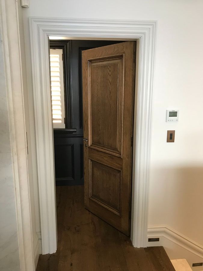 Partially Open Wooden Door in A White Hallway Showing a Dark Room Beyond — Fineworx Joinery in Warnervale, NSW