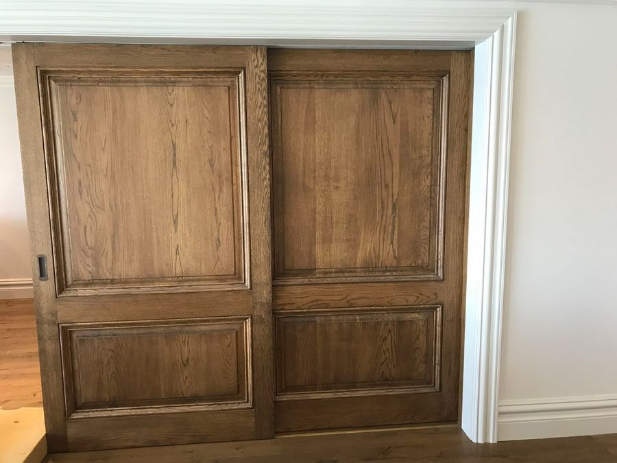 Wooden Double Cabinet Doors with Raised Panels Framed by White Molding in A Room — Fineworx Joinery in Warnervale, NSW