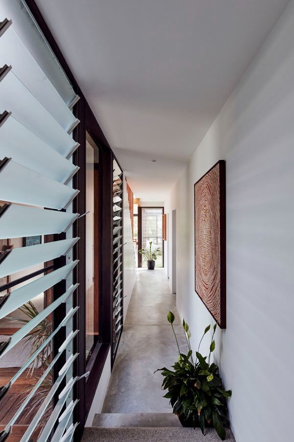 Narrow modern hallway with white walls, louvred windows, potted plants, and framed wall art. — Fineworx Joinery in Warnervale, NSW