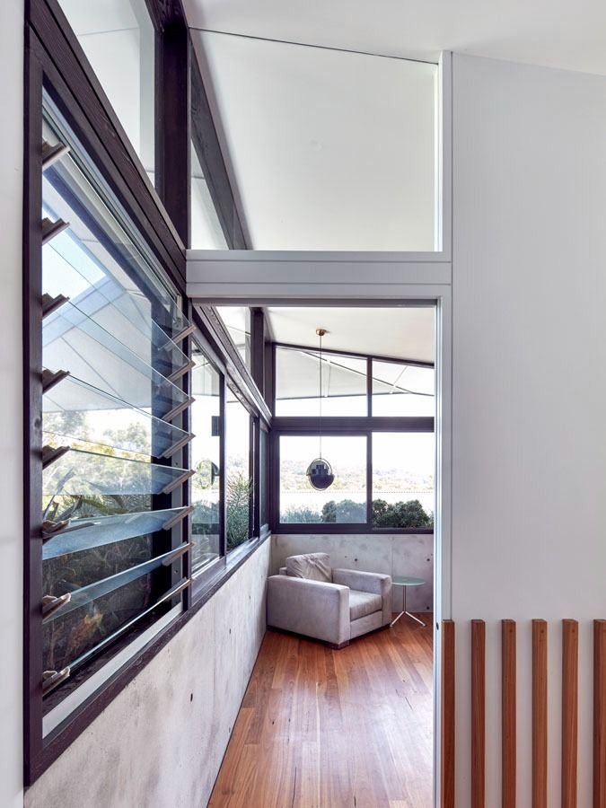 Bright modern hallway with wood floor, black-framed windows, and a white chair by a sunlit corner. — Fineworx Joinery in Warnervale, NSW