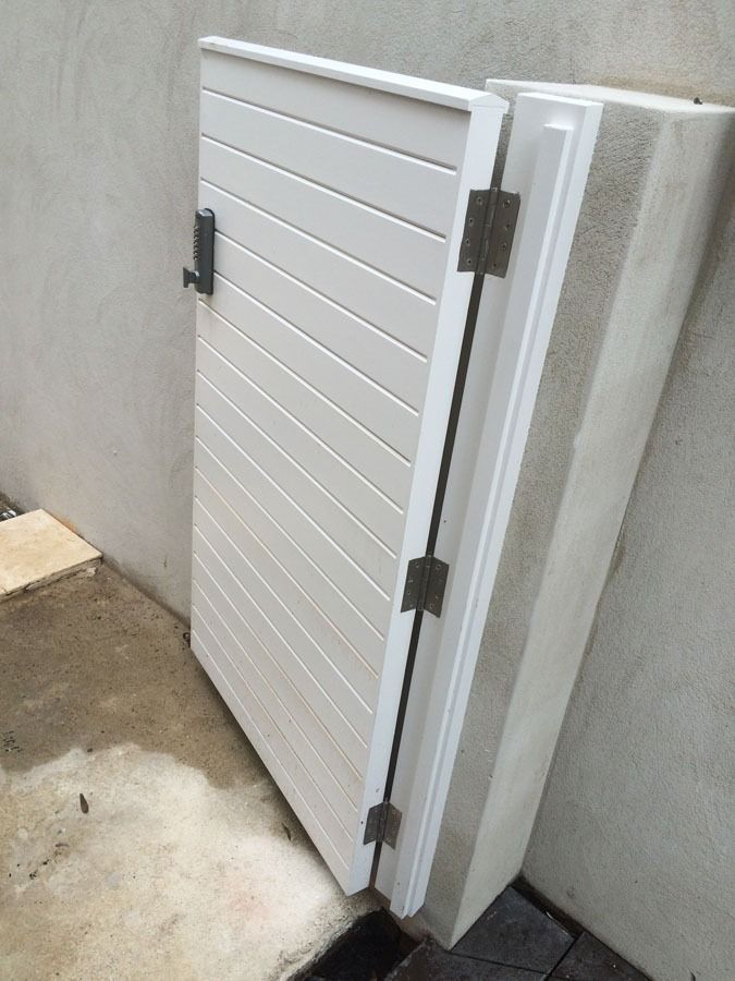 White Slatted Gate or Panel Leaning Against a Concrete Wall Outdoors — Fineworx Joinery in Warnervale, NSW