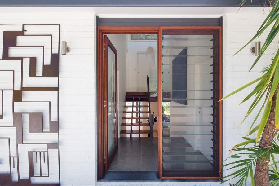 Modern house entryway with open front door, glass screen door, and decorative wall art — Fineworx Joinery in Warnervale, NSW
