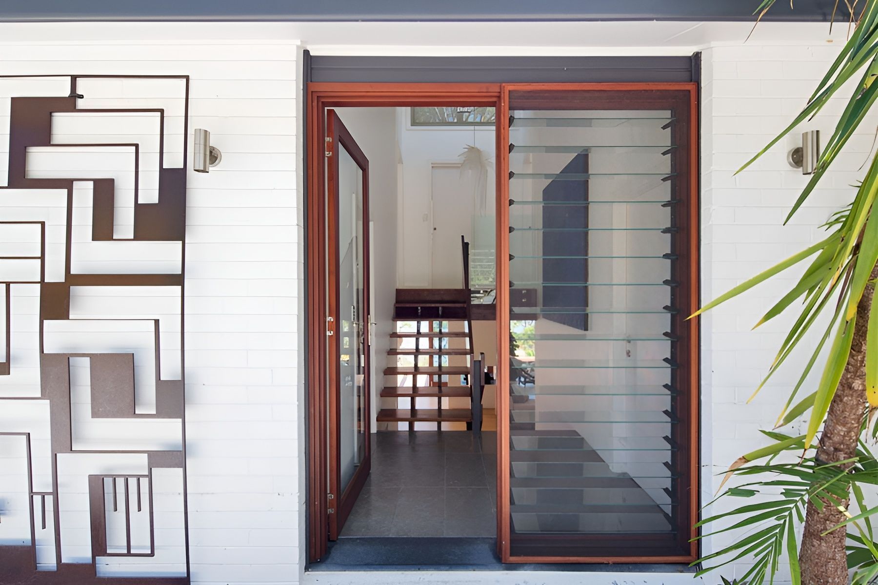 Front Entrance with Glass Door and Decorative Wall Art on A White Exterior Wall — Fineworx Joinery in Warnervale, NSW