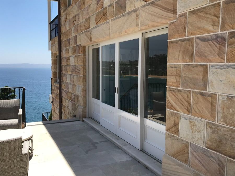 Patio Beside Stone House with Sliding Glass Doors Overlooking the Ocean — Fineworx Joinery in Warnervale, NSW