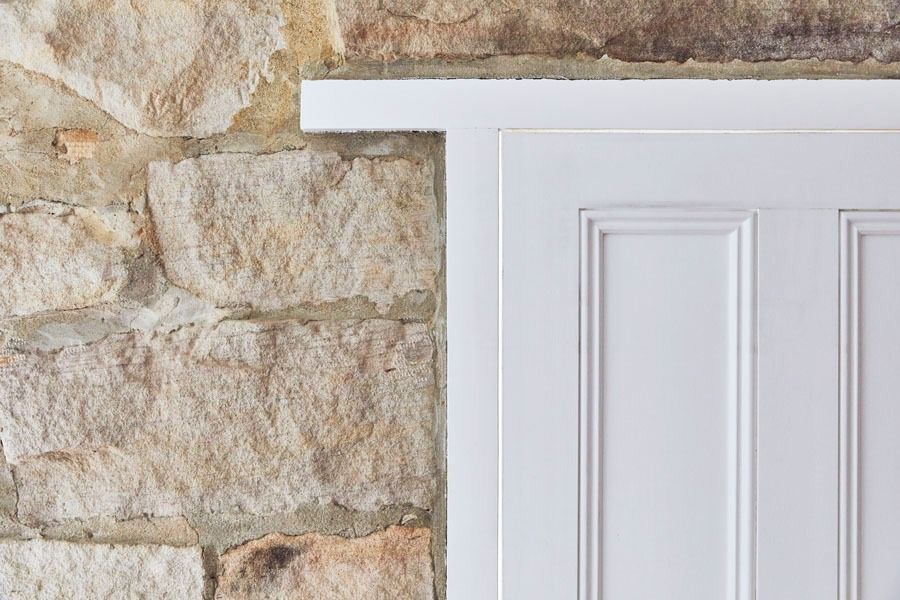 White Paneled Door Beside a Rustic Stone Wall — Fineworx Joinery in Warnervale, NSW