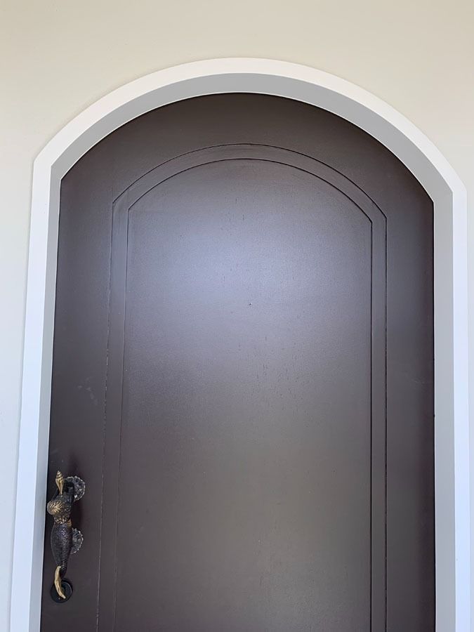 Closed Brown Arched Front Door with A Decorative Handle and White Trim — Fineworx Joinery in Warnervale, NSW