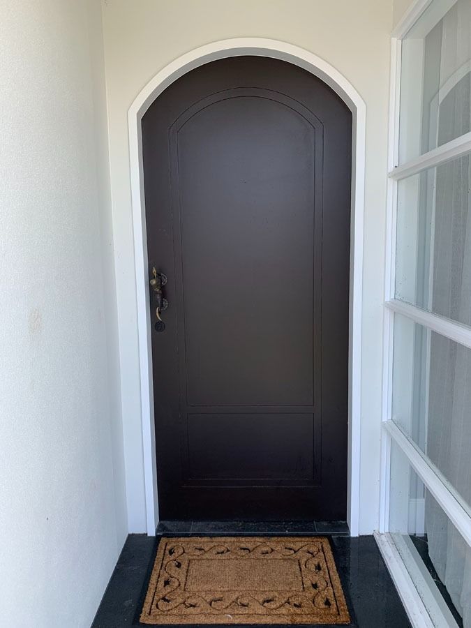 Front Door with Arched White Trim and Tan Doormat in A Narrow Entryway — Fineworx Joinery in Warnervale, NSW