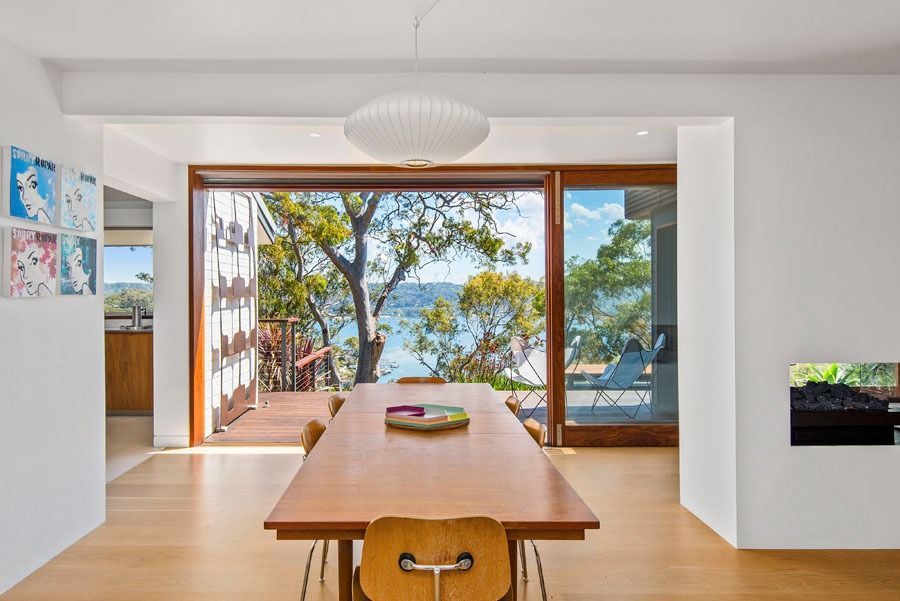 Modern Dining Room with Wooden Table and Open Sliding Doors — Fineworx Joinery in Warnervale, NSW