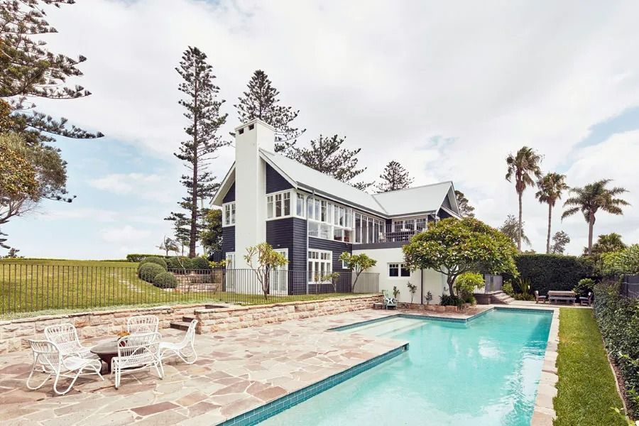 Modern House with A Turquoise Pool and Tall Palm Trees in A Landscaped Yard — Fineworx Joinery in Warnervale, NSW