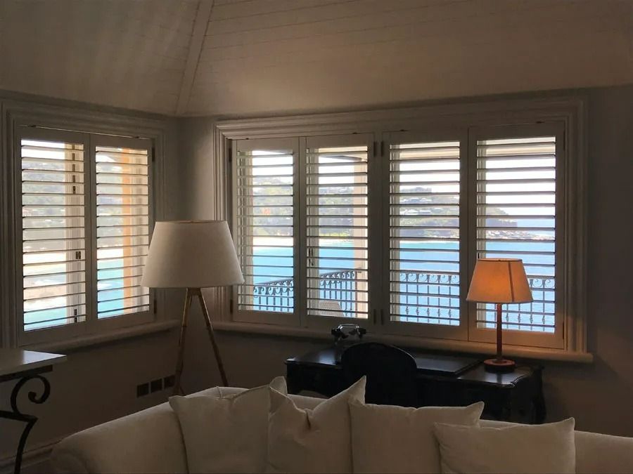 Living Room with Bay Windows, White Shutters and A Sofa with A Black Chair and Side Table — Fineworx Joinery in Warnervale, NSW