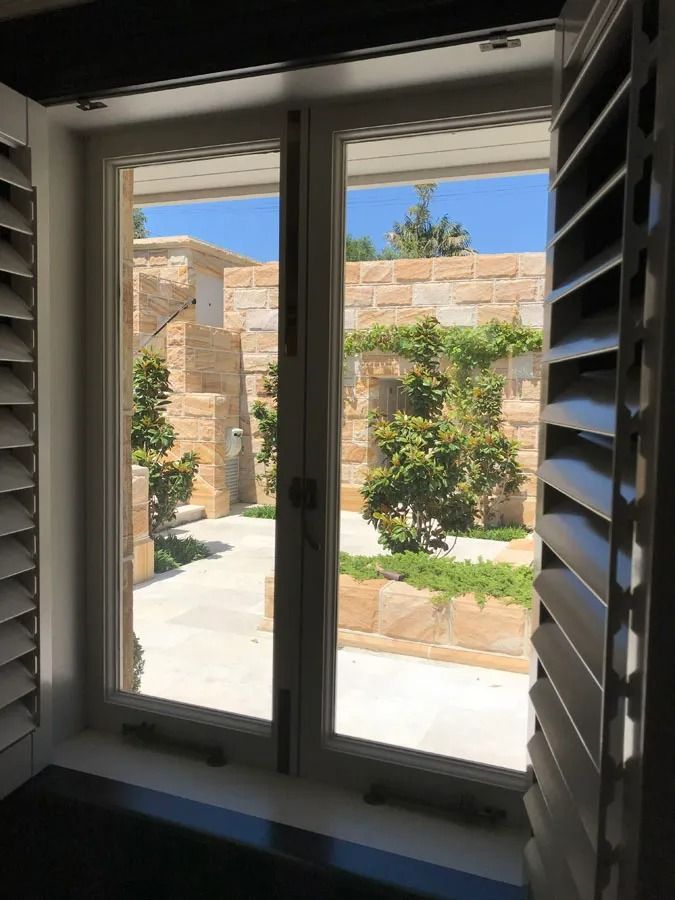 View Through a Window to A Sunny Courtyard with Stone Walls — Fineworx Joinery in Warnervale, NSW