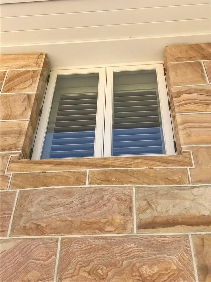 White Framed Window with Closed Shutters Set in A Tan Stone Exterior Wall — Fineworx Joinery in Warnervale, NSW