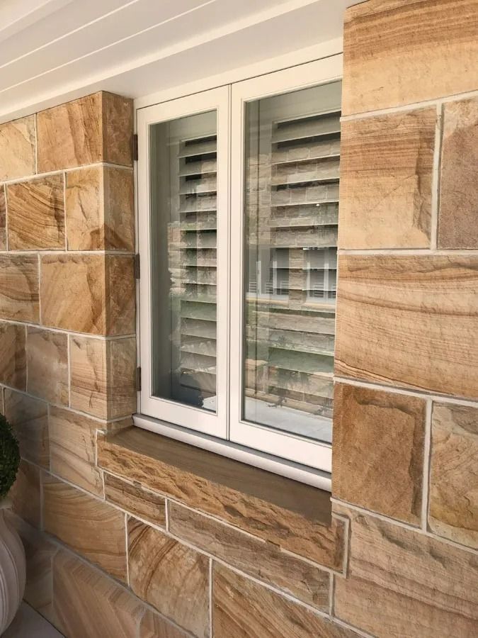 White Framed Shuttered Window Set in A Tan Stone Exterior Wall — Fineworx Joinery in Warnervale, NSW