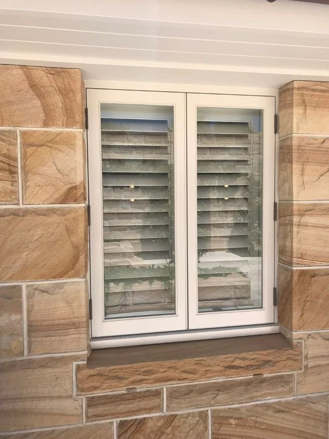 White Shuttered Window Set in A Tan Stone Wall with A Stone Sill and Trim — Fineworx Joinery in Warnervale, NSW